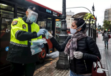 Un policía local entrega una mascarilla a una mujer en el centro de Valencia. / FOTO: Rober Solsona - Europa Press.