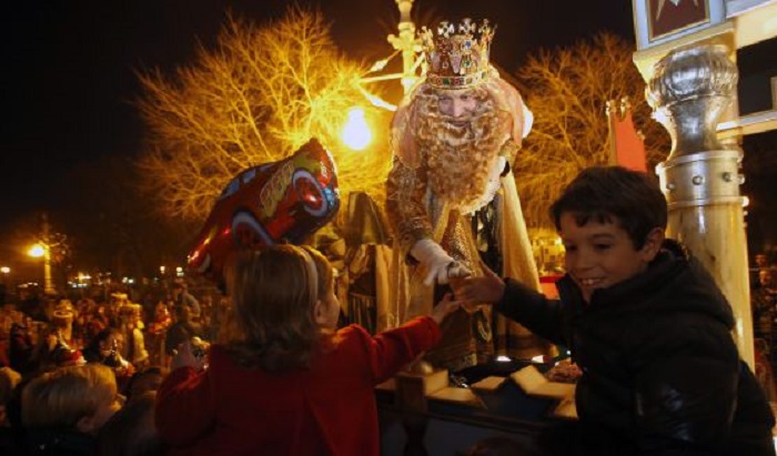 Los niños saludan a los reyes magos durante la cabalgata