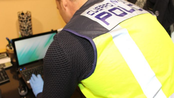 Agente de la Policía Nacional inspeccionando un ordenador por estafa