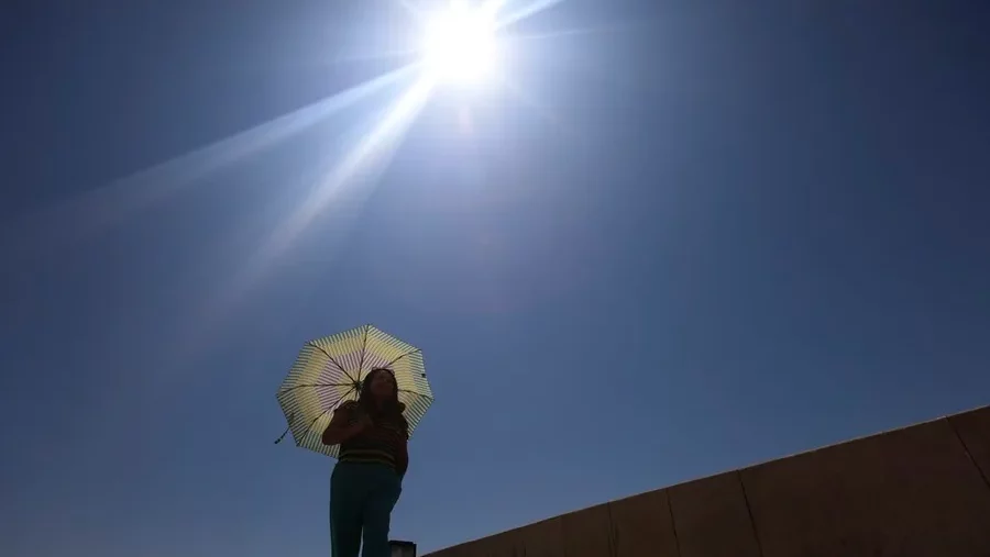 Una mujer se protege del sol con una sombrilla mientras camina. EFE/Salas