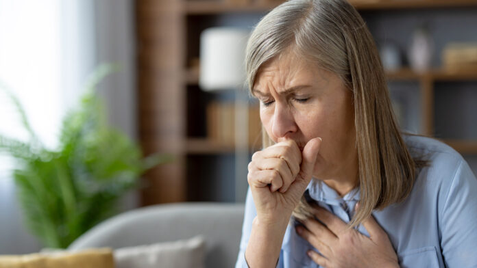 Mature woman coughing, feeling unwell in living room