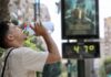 Una nueva ola de calor extremo activa la alerta roja en Valencia: temperaturas de hasta 45 grados Un hombre hidratándose frente a un termómetro de calle que muestra la ola de calor