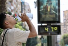 Una nueva ola de calor extremo activa la alerta roja en Valencia: temperaturas de hasta 45 grados Un hombre hidratándose frente a un termómetro de calle que muestra la ola de calor