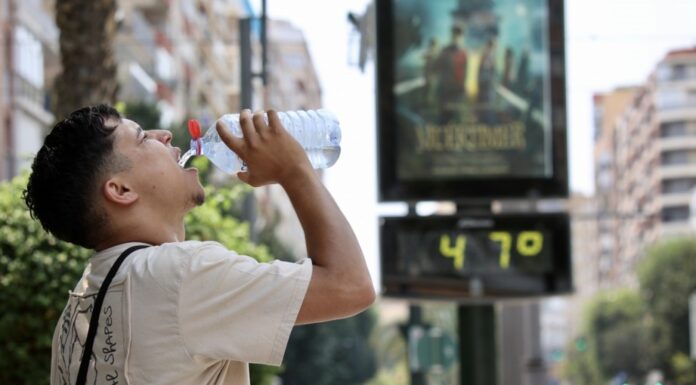 Una nueva ola de calor extremo activa la alerta roja en Valencia: temperaturas de hasta 45 grados Un hombre hidratándose frente a un termómetro de calle que muestra la ola de calor