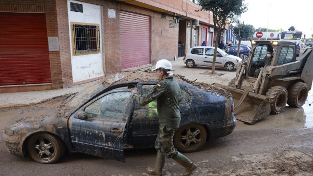 Varios militares colaboran con vecinos y voluntarios en la retirada de vehículos en la localidad de Catarroja. / ANA ESCOBAR (EFE)