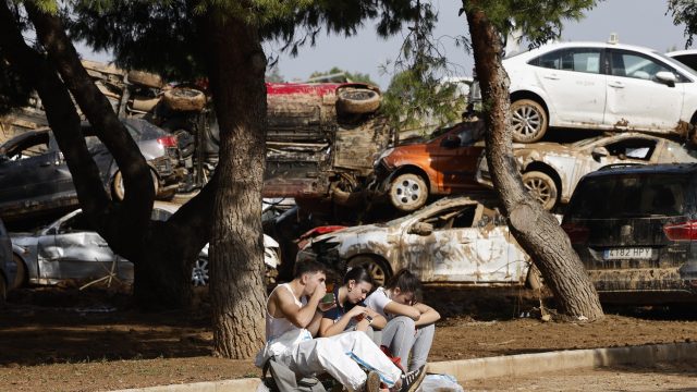 Varias personas descansan junto a los vehículos apilados en Catarroja. / ANA ESCOBAR (EFE) Sacar las emociones es fundamental para superar la catastrofé
