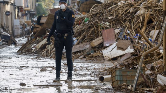 Un miembro de la Policía junto a una montaña de escombros en Catarroja. EFE/ Chema Moya